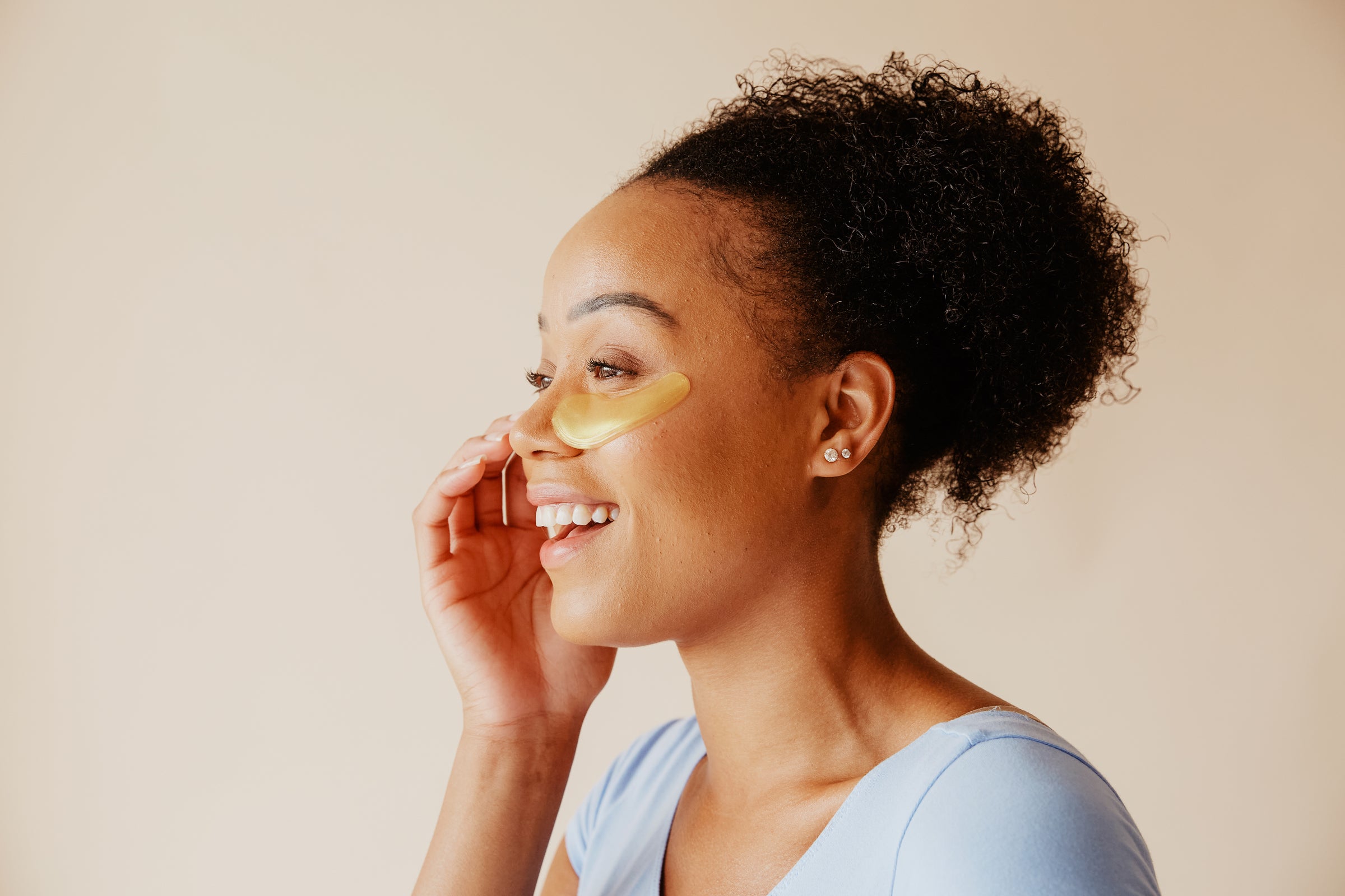 Woman with under eye patches smiling sideways